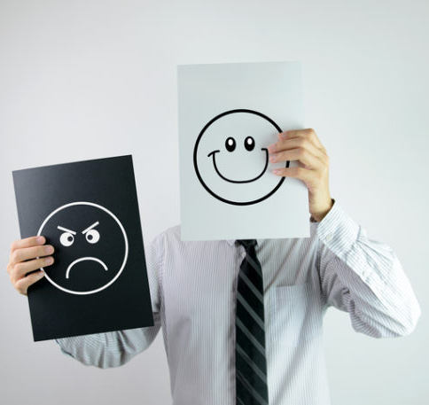 Businessman holding two papers with happy and angry face each on them